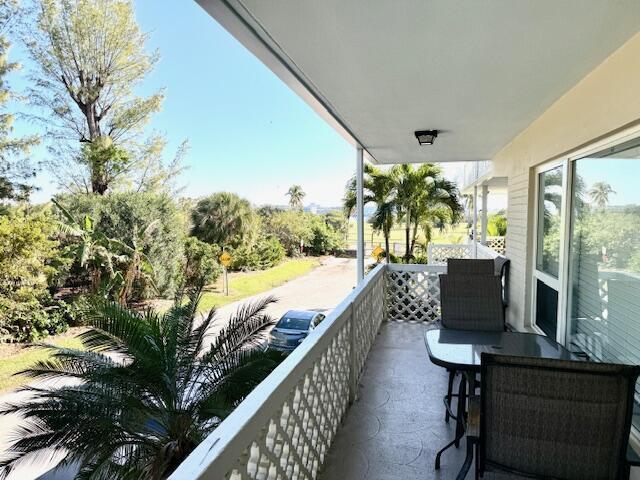 A covered balcony features a table and chairs overlooking a street, palm trees, and greenery — 131 N Golfview Road # 4, Lake Worth FL 33460, LAKE WORTH, FL