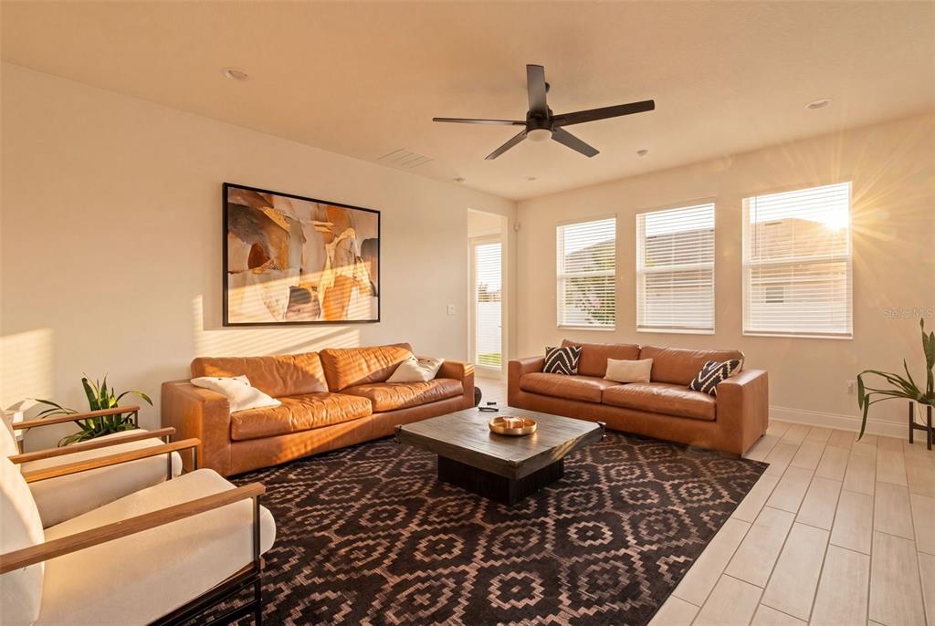 A living room features two leather sofas, a patterned area rug, and a ceiling fan — 700 ALBYON COURT, DEBARY, FL