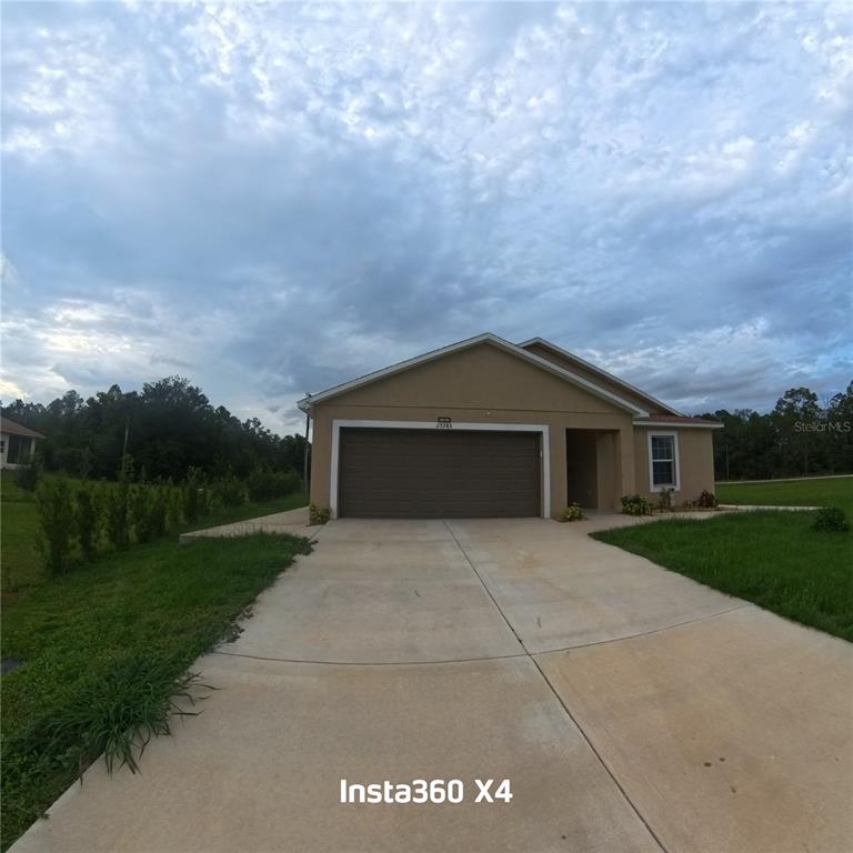 A tan single-story house with a two-car garage and a concrete driveway — 25283 CANTERBURY DRIVE, LAKE WALES, FL