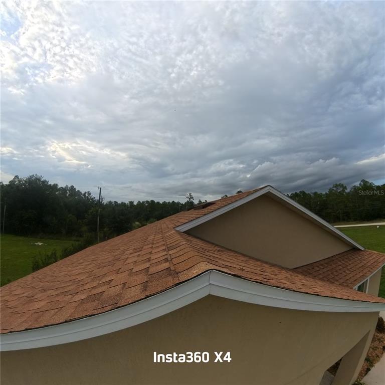 An elevated view shows the shingled roof and exterior wall of a residential building — 25283 CANTERBURY DRIVE, LAKE WALES, FL