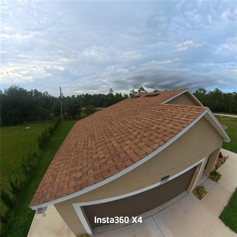An elevated view of a house roof with brown shingles and a garage below — 25283 CANTERBURY DRIVE, LAKE WALES, FL