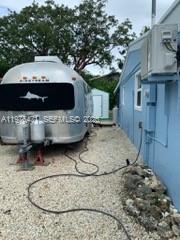 An Airstream trailer is parked on a gravel lot next to a blue building — 919 Lobster Ln # 0, Key Largo FL 33037, KEY LARGO, FL