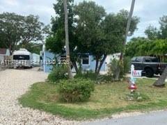 A light blue house sits on a gravel lot with a parked trailer and truck — 919 Lobster Ln # 0, Key Largo FL 33037, KEY LARGO, FL