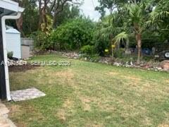 A grassy backyard features a small white shed and lush trees along the back fence — 919 Lobster Ln # 0, Key Largo FL 33037, KEY LARGO, FL
