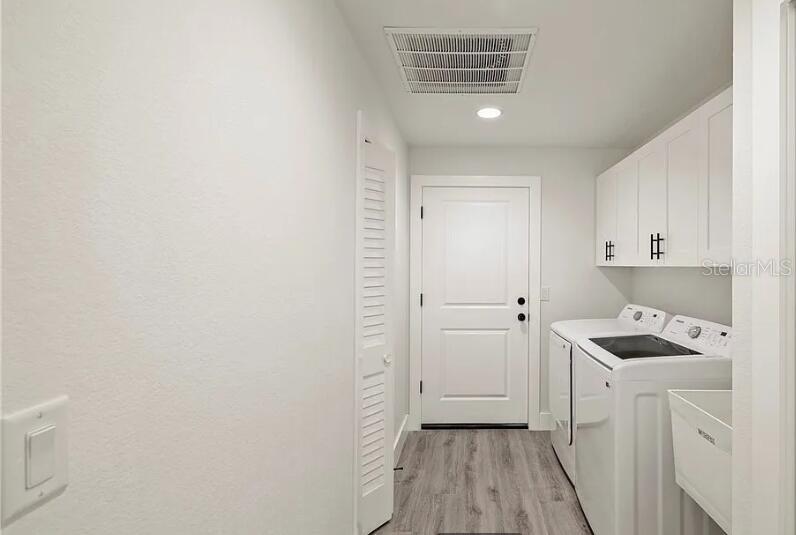 A laundry room features white cabinets, a washer, a dryer, and a utility sink — 130 HALLMARK AVENUE, LAKE PLACID, FL