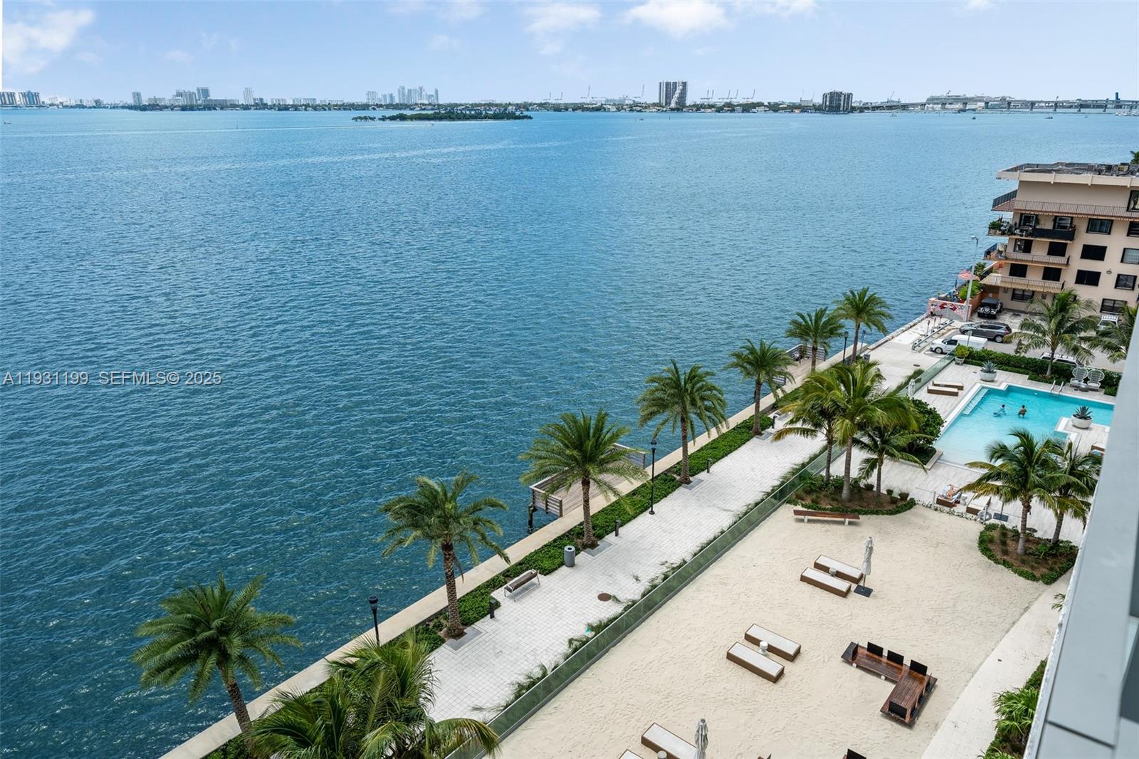 An elevated view of a waterfront pool deck with palm trees and sandy lounge areas — 2900 NE 7th Ave # 604, Miami FL 33137, MIAMI, FL