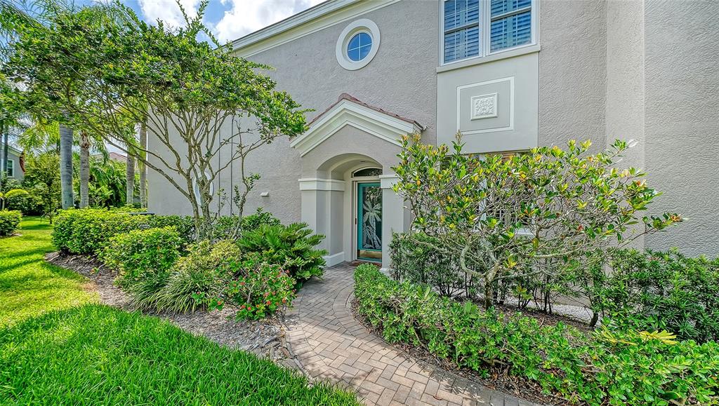 A paved walkway leads to the front entrance of a two-story home with landscaping — 5211 PARISIENNE PLACE UNIT 101B27, SARASOTA, FL