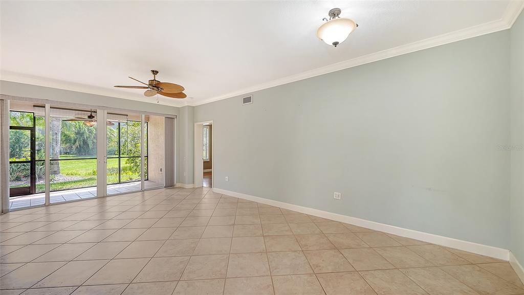 A spacious living room features light blue walls, tile flooring, and sliding glass patio doors — 5211 PARISIENNE PLACE UNIT 101B27, SARASOTA, FL