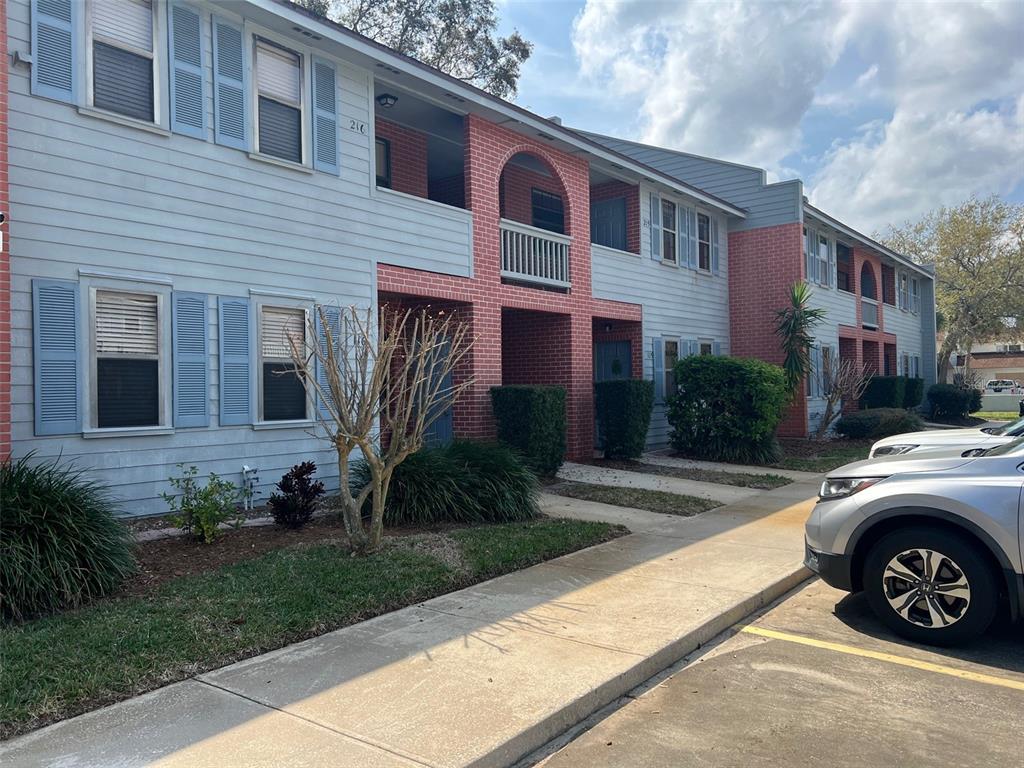 A two-story apartment building with light blue siding, red brick accents, and a concrete sidewalk — 1795 HARRISON STREET UNIT 215, TITUSVILLE, FL