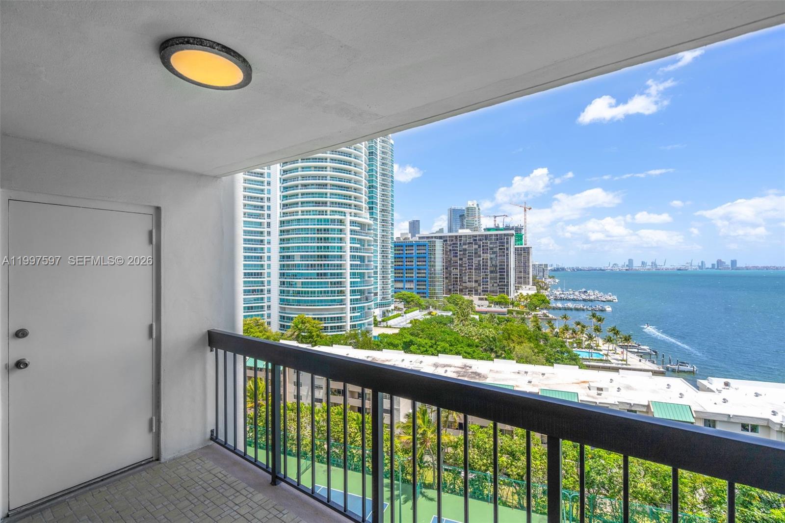 A balcony overlooks a coastal city skyline, a marina, and a tennis court below — 2333 Brickell Ave # 1109, Miami FL 33129, MIAMI, FL