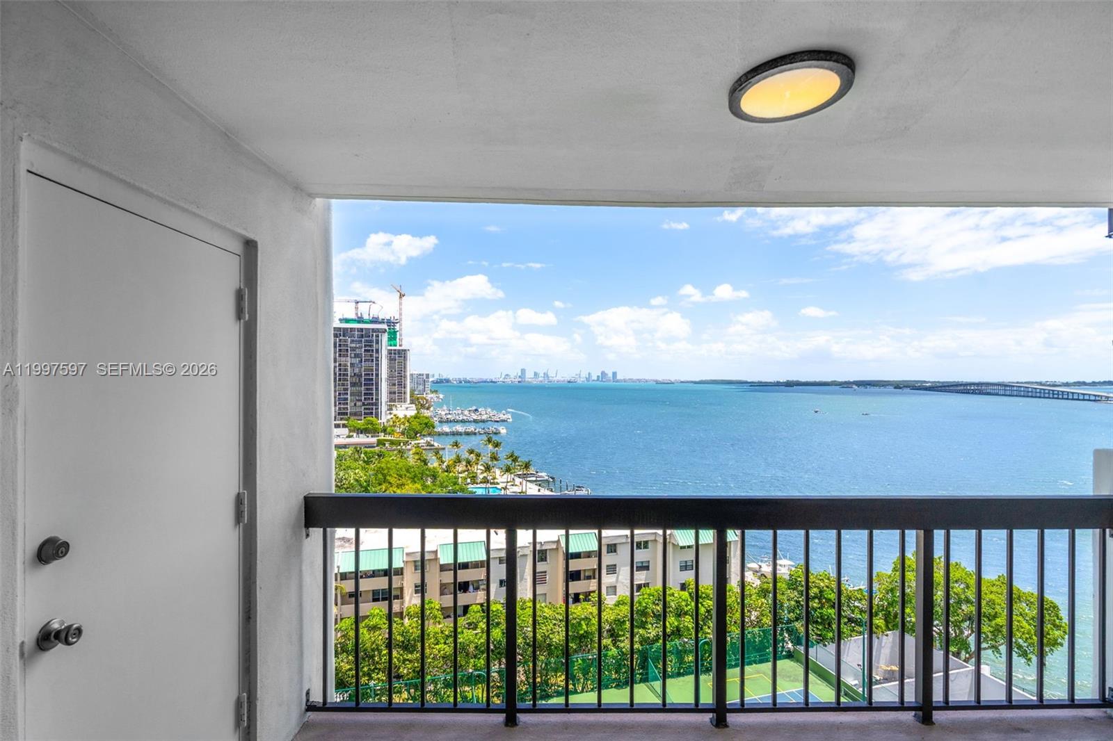A balcony with a black railing overlooks a bay, a tennis court, and a city skyline — 2333 Brickell Ave # 1109, Miami FL 33129, MIAMI, FL