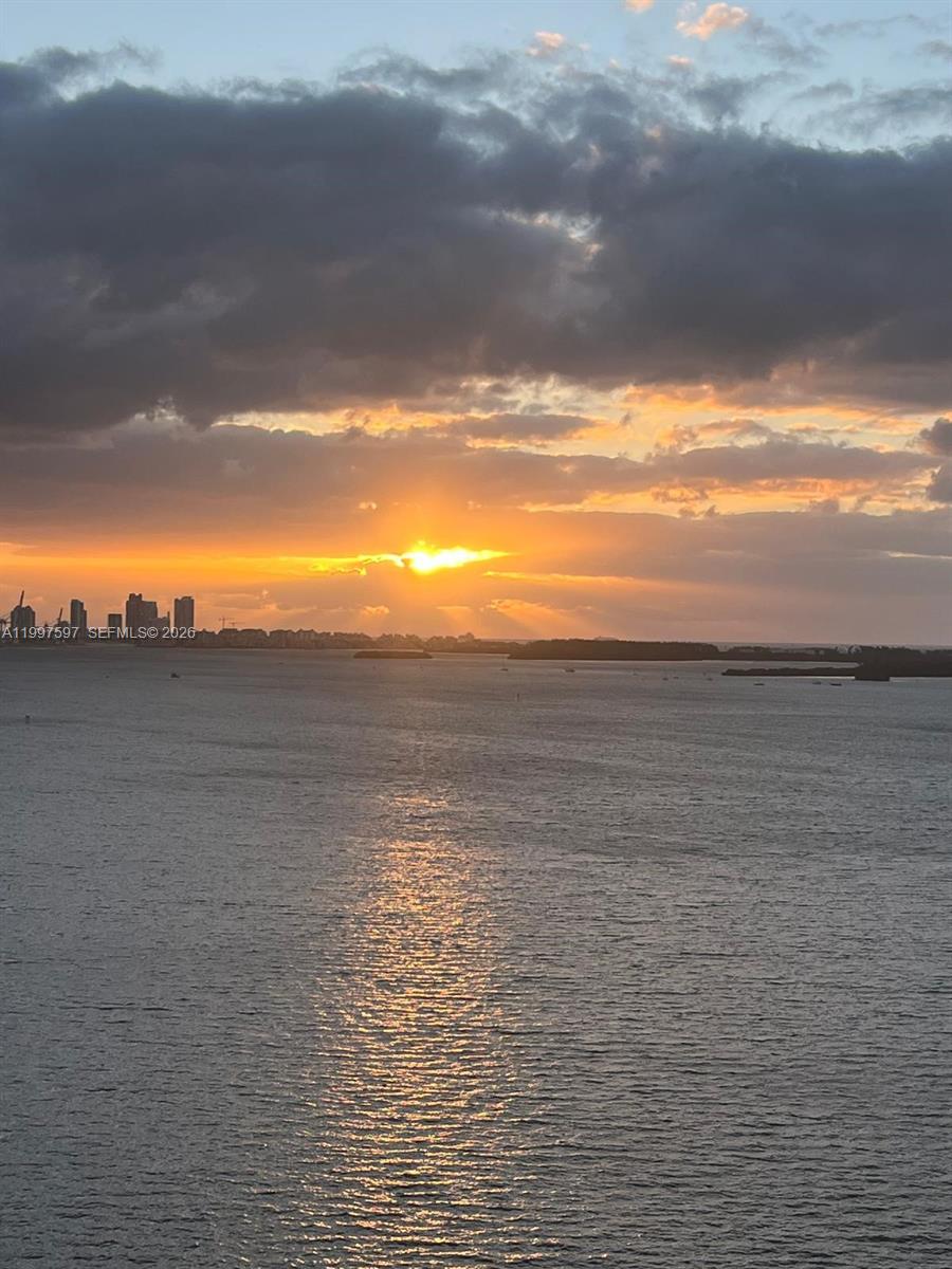 A view of a sunset over a body of water with a distant city skyline — 2333 Brickell Ave # 1109, Miami FL 33129, MIAMI, FL