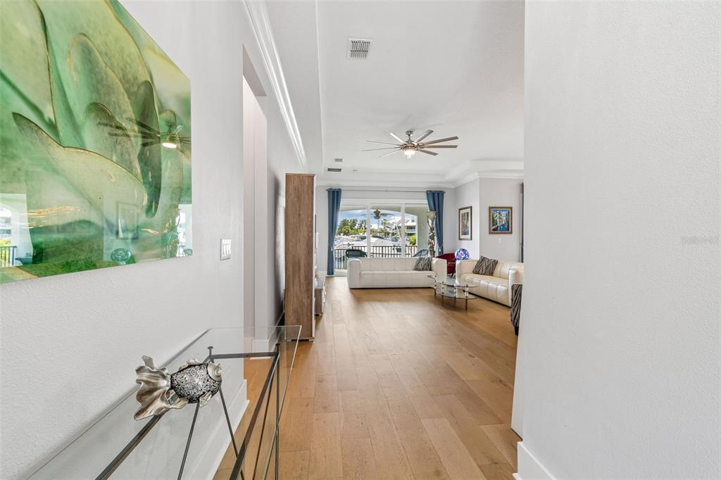 A hallway leads into a living room with light wood floors and a waterfront view — 3036 CHRISTOPHERS WATCH LANE, RUSKIN, FL