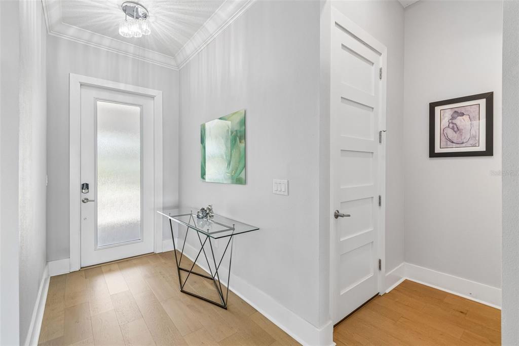 A bright entryway features light wood flooring, a glass console table, and a white door — 3036 CHRISTOPHERS WATCH LANE, RUSKIN, FL