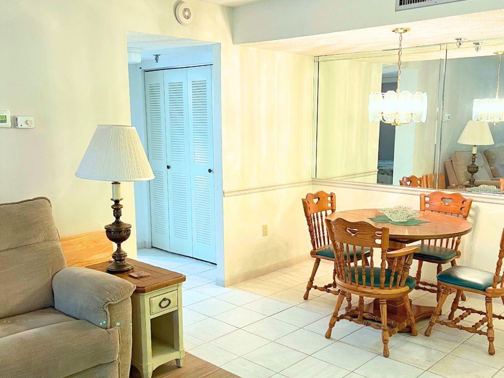A dining area features a round wooden table, four chairs, and a mirrored wall — 3006 CARING WAY UNIT 329, PORT CHARLOTTE, FL