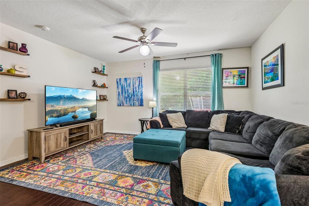 A living room features a dark sectional sofa, a large television, and a colorful area rug — 806 GRAND PARK COURT, DELAND, FL