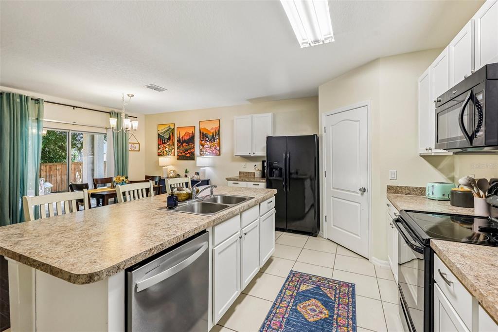 A kitchen features white cabinets, a large island with a sink, and black appliances — 806 GRAND PARK COURT, DELAND, FL