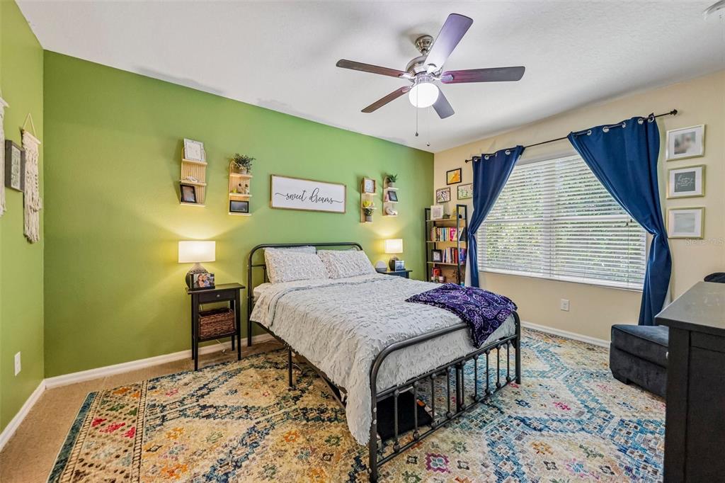 A bedroom features a green accent wall, a metal bed frame, and a patterned rug — 806 GRAND PARK COURT, DELAND, FL