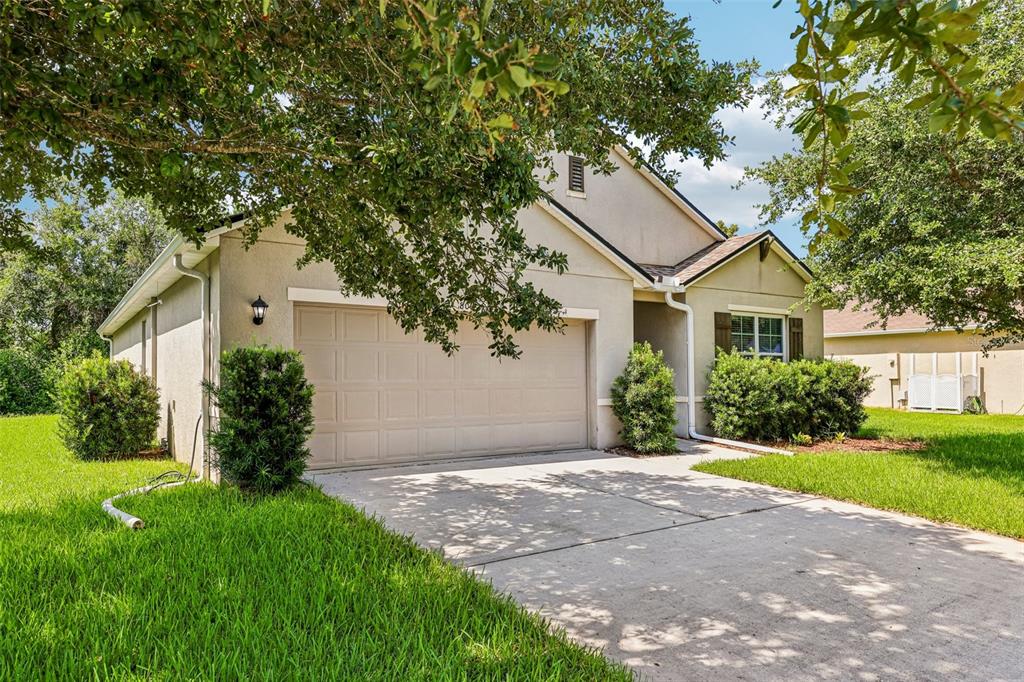 A beige single-story house with a two-car garage and a concrete driveway — 806 GRAND PARK COURT, DELAND, FL