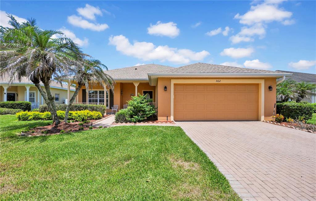 A single-story house with a tan stucco exterior, a two-car garage, and a palm tree — 362 LAKE CASSIDY DRIVE, POINCIANA, FL