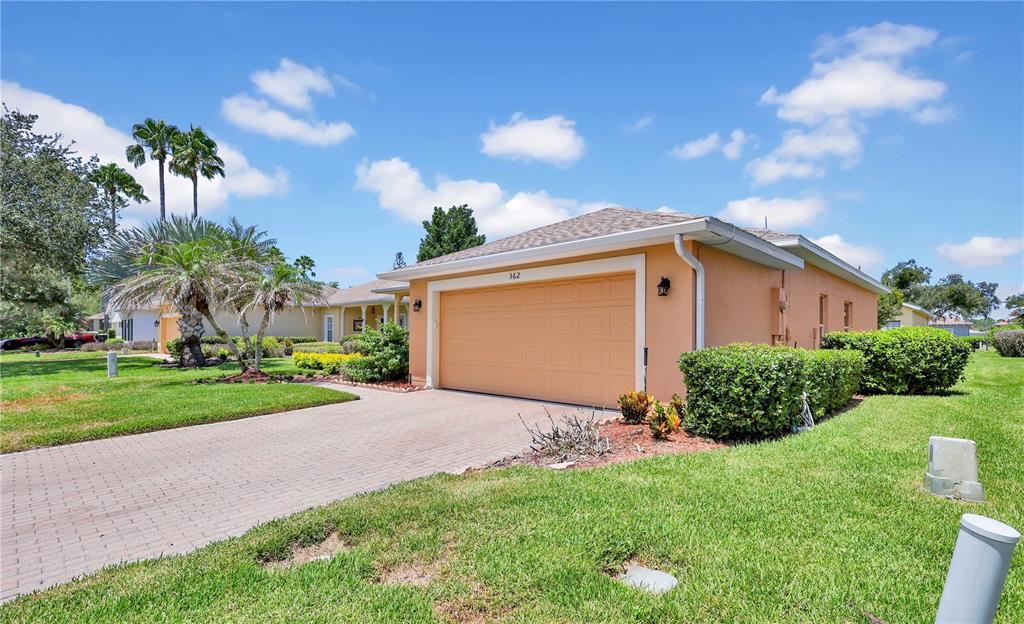 A peach-colored house with a two-car garage and a paved driveway under a blue sky — 362 LAKE CASSIDY DRIVE, POINCIANA, FL