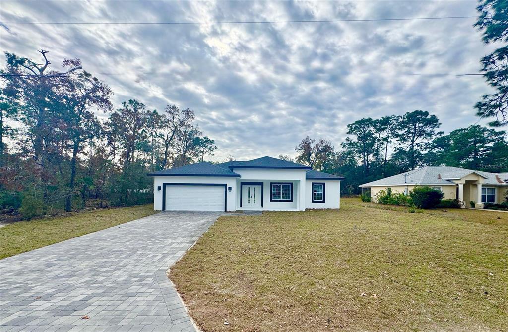 A modern, white single-story house with a dark roof and a paved driveway — 3284 W GATES LANE, CITRUS SPRINGS, FL
