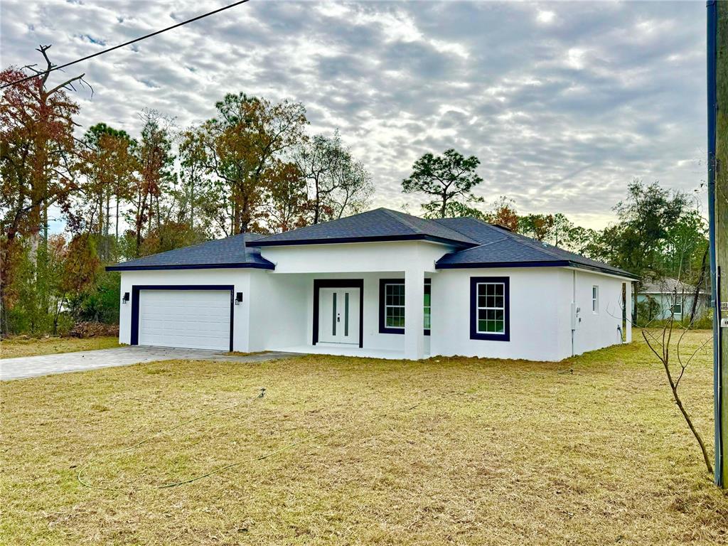 A white single-story house with a dark roof and a two-car garage sits on grass — 3284 W GATES LANE, CITRUS SPRINGS, FL