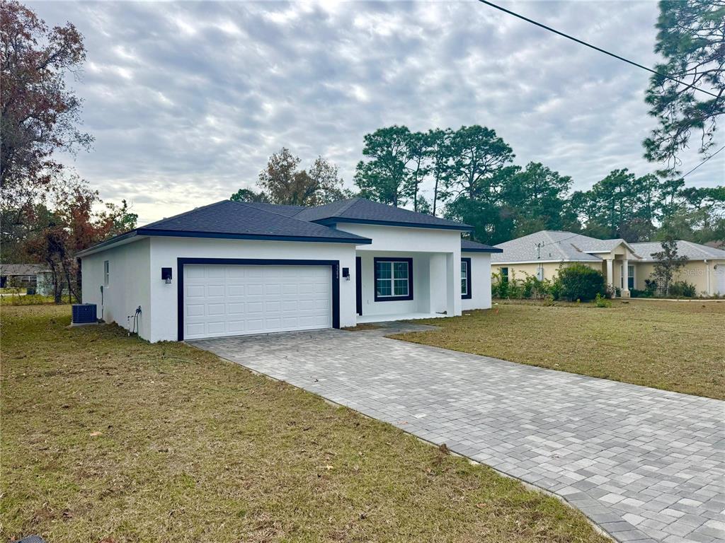 A modern, white single-story house with a dark roof and a paved driveway — 3284 W GATES LANE, CITRUS SPRINGS, FL