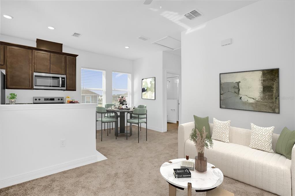 This open-concept living and dining area features carpeted floors, dark wood cabinets, and neutral walls — 3008 MIRAGE PLACE, ST CLOUD, FL