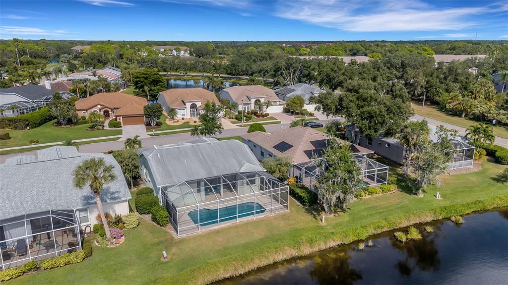 An aerial view shows several suburban houses with swimming pools and screened lanais near a lake — 8976 WHITEMARSH AVENUE, SARASOTA, FL