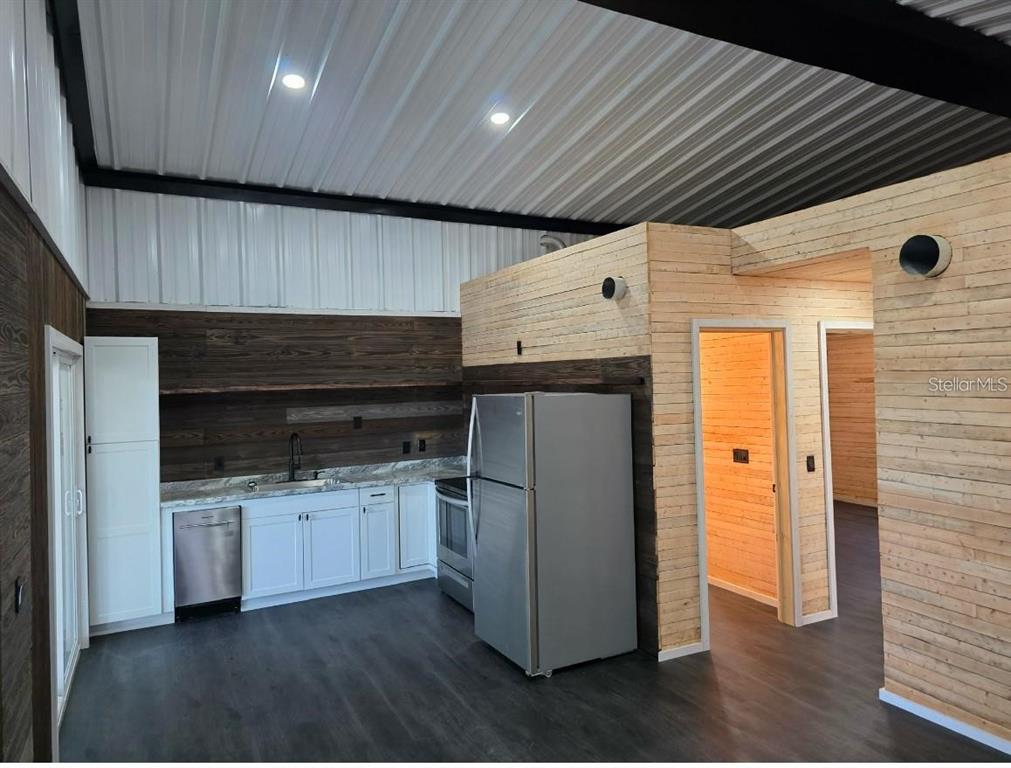 A kitchen features white cabinets, stainless steel appliances, and wood-paneled walls under a metal ceiling — 401 SW KEMP COURT UNIT Suite B, LAKE CITY, FL