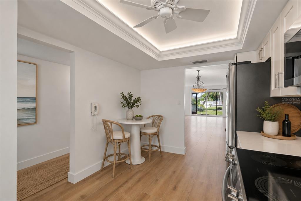 A kitchen with a small dining area, white cabinetry, and light wood-look flooring — 5600 BEACH WAY DRIVE UNIT 111, SARASOTA, FL