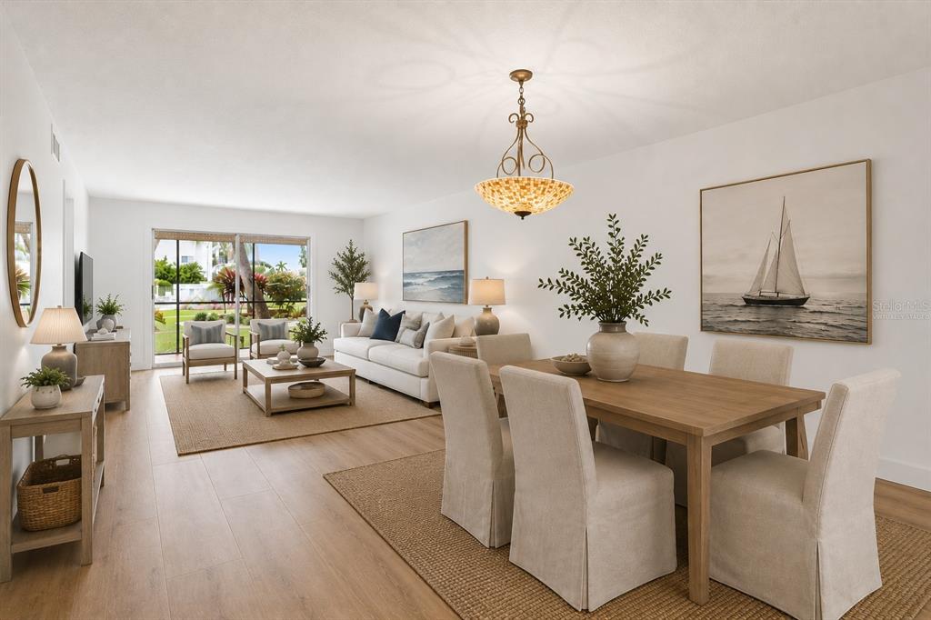 A living and dining room with light wood floors, neutral furniture, and a sliding glass door — 5600 BEACH WAY DRIVE UNIT 111, SARASOTA, FL