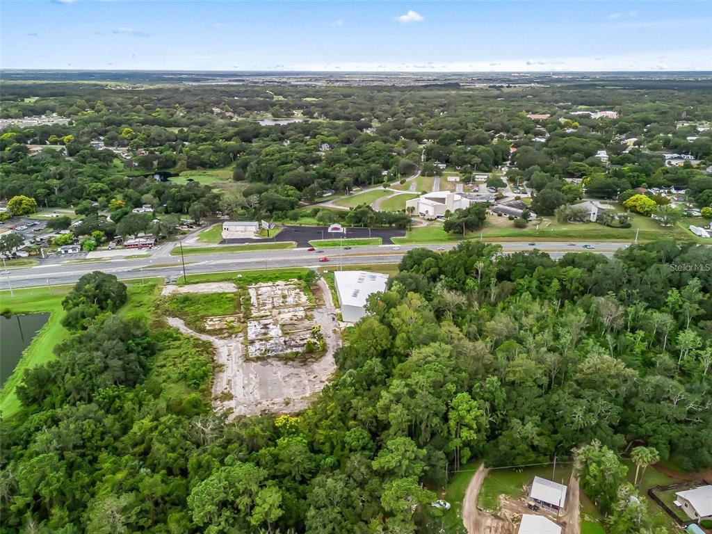 An aerial view shows a cleared lot with a building foundation next to a highway — 3155 US HIGHWAY 441/27, FRUITLAND PARK, FL