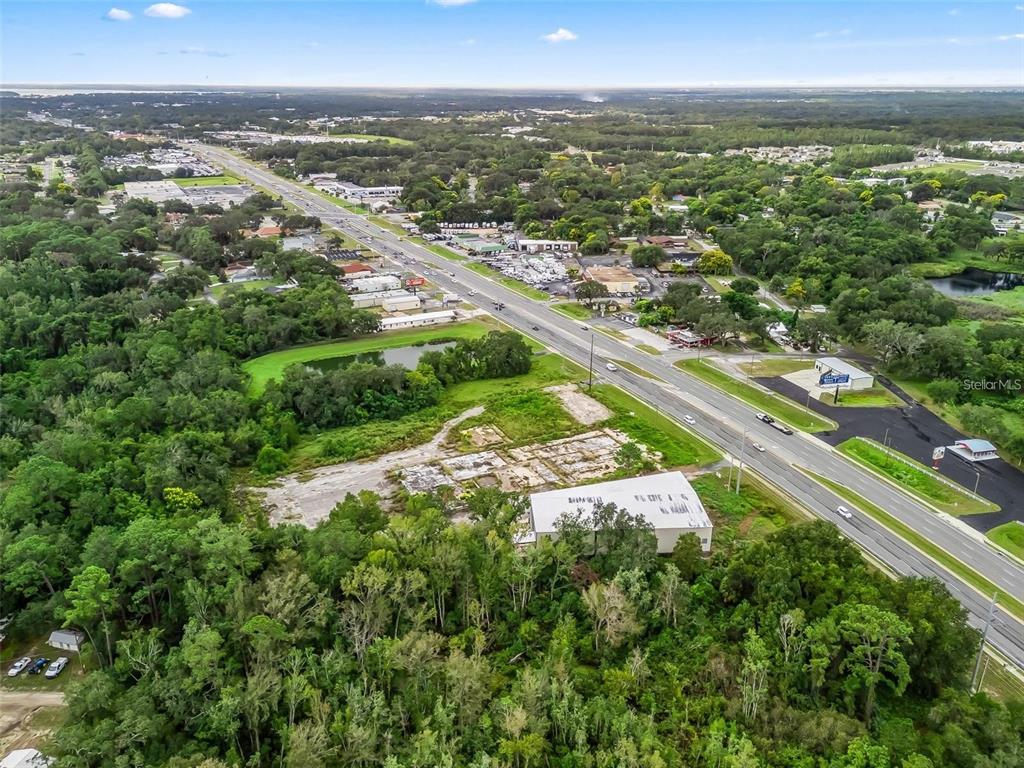 An aerial view shows a commercial building and a cleared lot beside a highway — 3155 US HIGHWAY 441/27, FRUITLAND PARK, FL