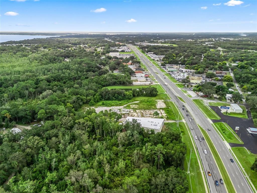 An aerial view shows a commercial building and vacant land adjacent to a multi-lane highway — 3155 US HIGHWAY 441/27, FRUITLAND PARK, FL