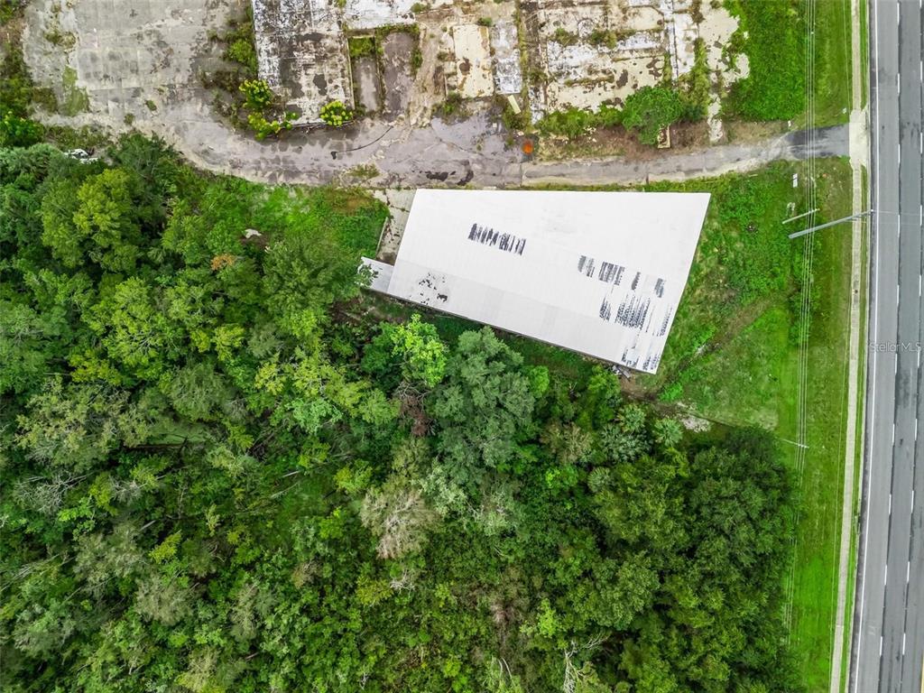 An aerial view shows a white rectangular building surrounded by dense trees and paved areas — 3155 US HIGHWAY 441/27, FRUITLAND PARK, FL
