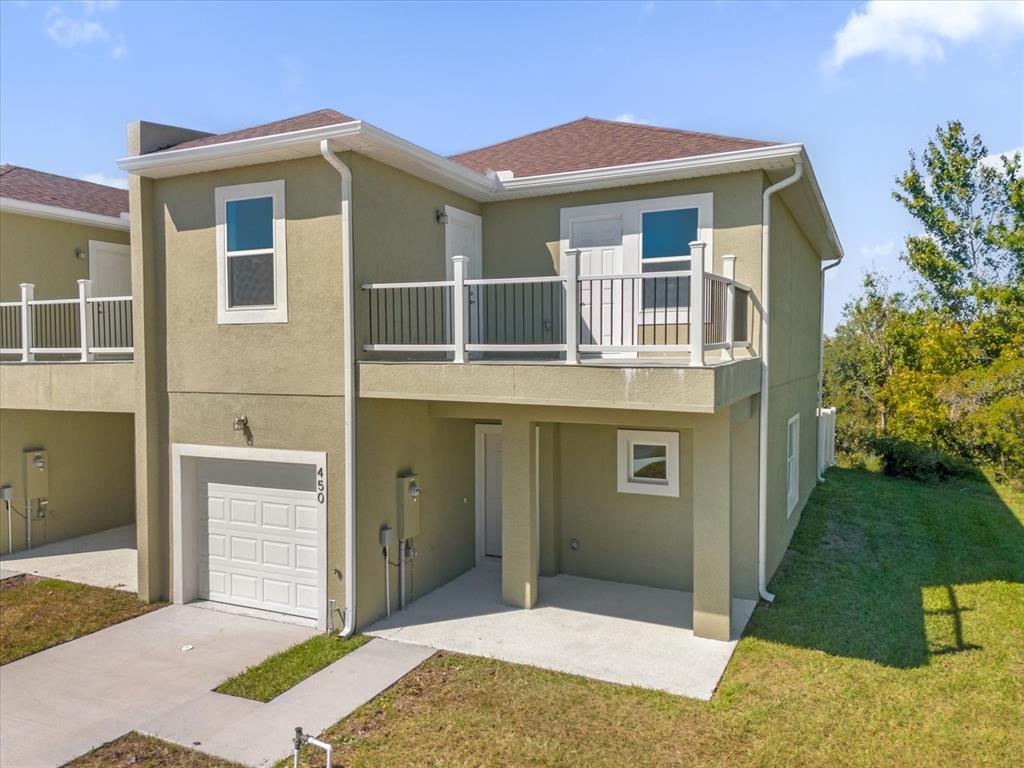 An exterior view of a two-story townhouse with a garage, balcony, and concrete patio — 450 LAKE SHORE PARKWAY, DAVENPORT, FL