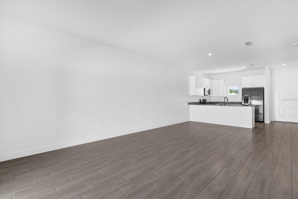An open-concept living area with white walls and gray wood-look tile flooring — 450 LAKE SHORE PARKWAY, DAVENPORT, FL