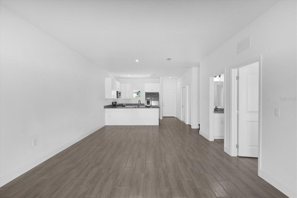 An open-concept living area features wood-look tile flooring, white walls, and a modern kitchen — 450 LAKE SHORE PARKWAY, DAVENPORT, FL
