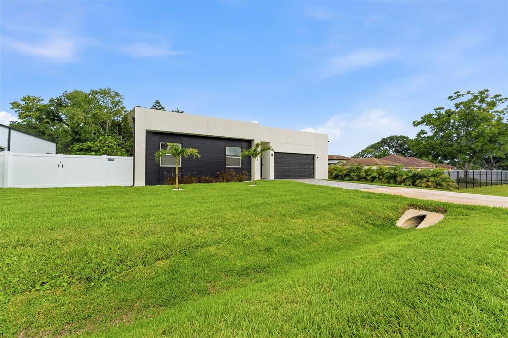 A modern, single-story house with a black facade and white trim sits on a grassy lot — 9714 VAN STREET, TAMPA, FL