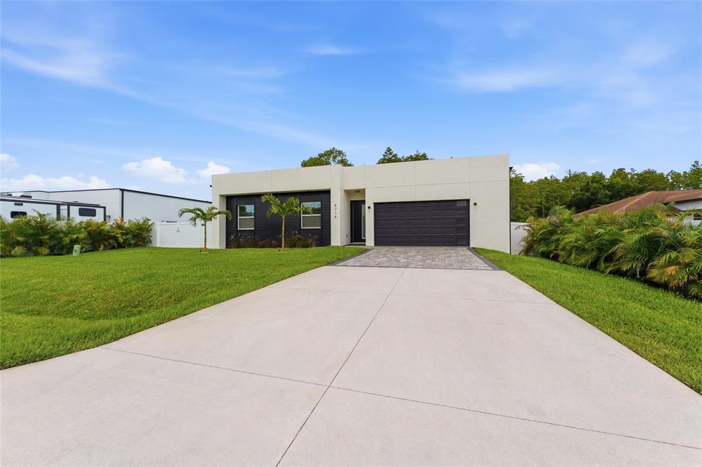 A modern, single-story house with a flat roof, white facade, and a dark garage door — 9714 VAN STREET, TAMPA, FL