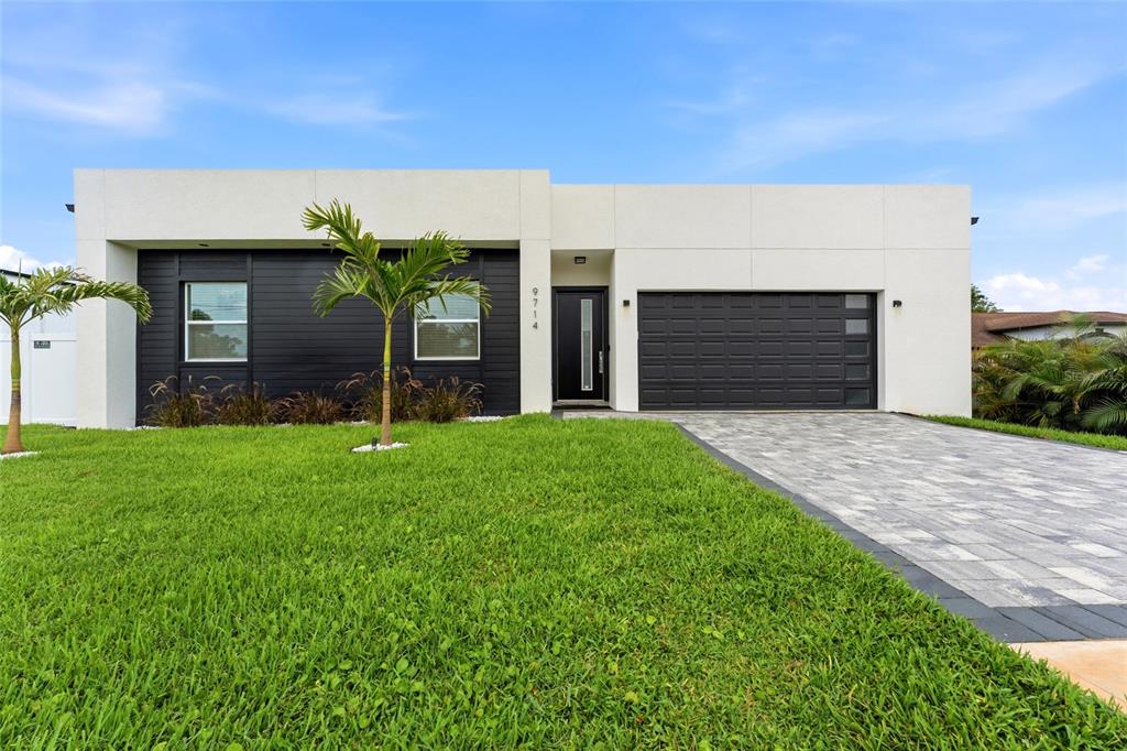 A modern, single-story house features a white facade, black horizontal siding, and a paved driveway — 9714 VAN STREET, TAMPA, FL