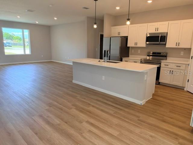 A kitchen with white cabinets and a center island opens into a spacious living area — 5792 SW 117TH LANE ROAD, OCALA, FL