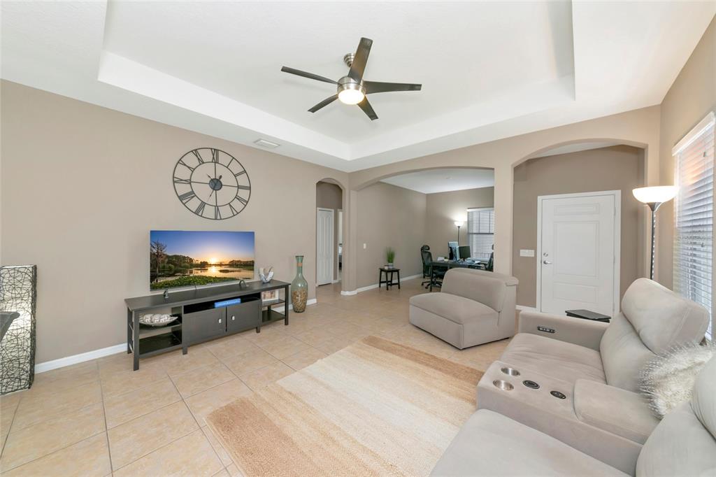 A living room features tile flooring, a tray ceiling with a fan, and a television console — 4930 NEWPORT NEWS CIRCLE, BRADENTON, FL