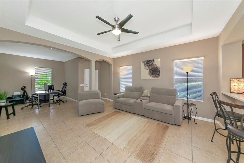 A living room with tile floors, a tray ceiling, and an adjacent home office area — 4930 NEWPORT NEWS CIRCLE, BRADENTON, FL
