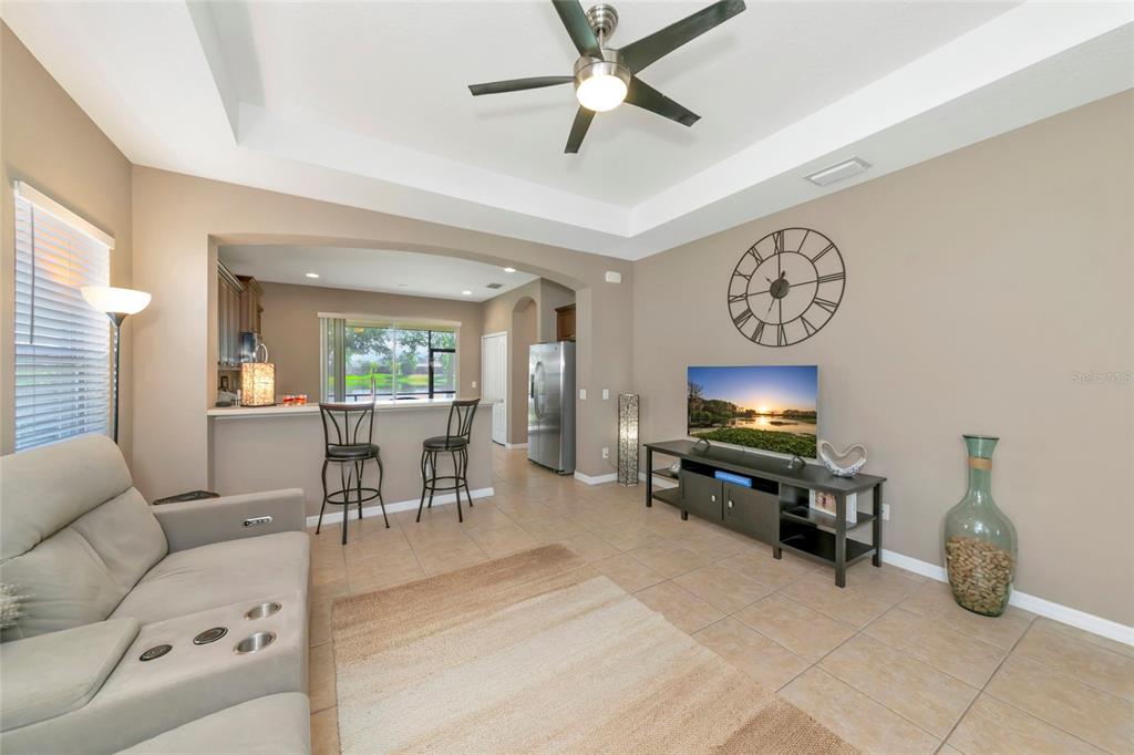 A living room with a sofa, television, and breakfast bar opening into a kitchen — 4930 NEWPORT NEWS CIRCLE, BRADENTON, FL