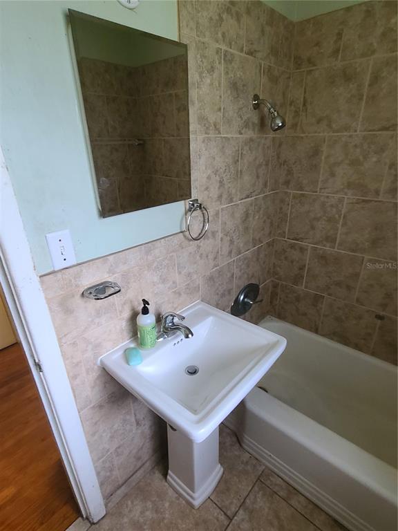 A bathroom features a pedestal sink, a tiled wall, and a combined shower and tub — 217 NW 36TH STREET, GAINESVILLE, FL
