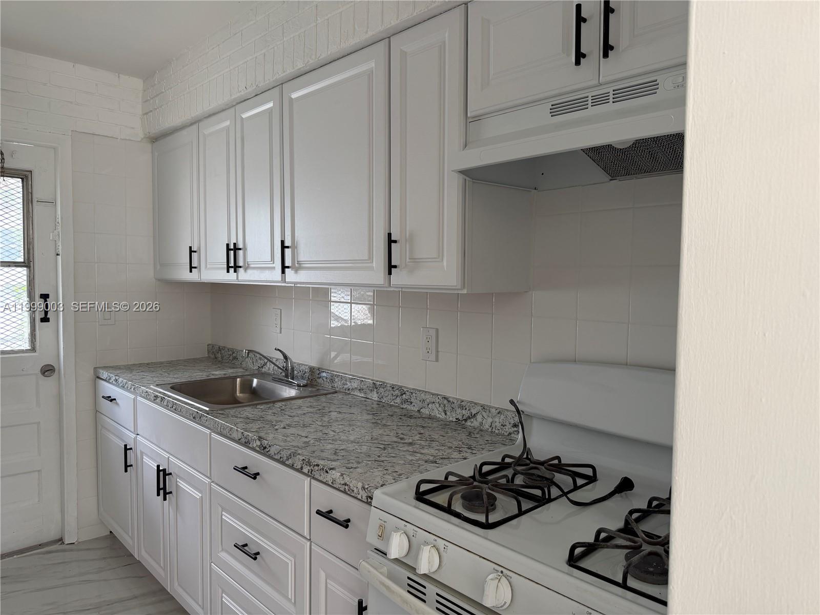 A kitchen features white cabinets, granite countertops, a stainless steel sink, and a gas stove — 9283 SW 39th St, Miami FL 33165, MIAMI, FL