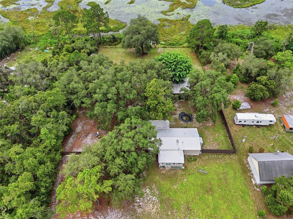 An aerial view shows a house with a metal roof surrounded by trees and grass — 31622 ANOTHER ANNA ROAD, DELAND, FL